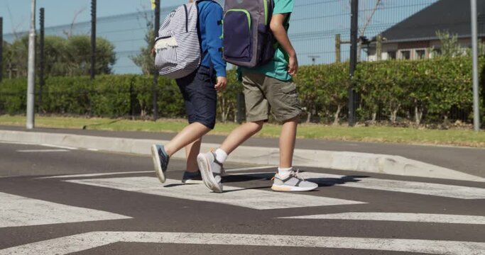 Two boys with school bags crossing the road
