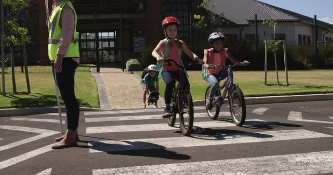 Two girls with school bags riding bicycles and crossing the road