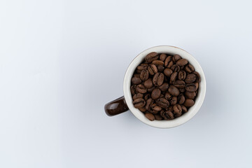A heap of brazilian coffee beans in a cup, studio photo on a white background, top view