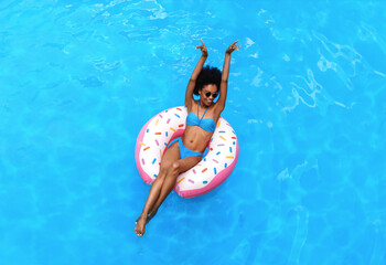 Carefree young girl enjoying relaxing day in pool, floating on inflatable ring, above view