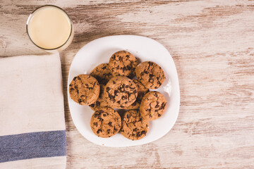 some chocolate cookies on a white plate with a glass of milk