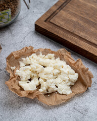 Farm grain ricotta cheese wrapped in kraft paper on stone table