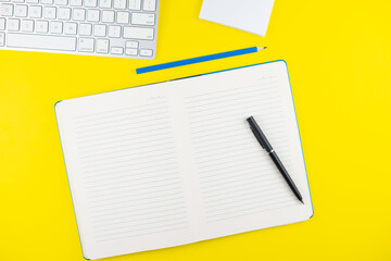 Fototapeta na wymiar Black pen, notepad planner, pencil and keyboard on yellow background. Flat lay. Copy space. Workplace in the office.