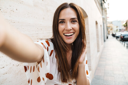 Image of cheerful beautiful woman taking selfie photo and smiling