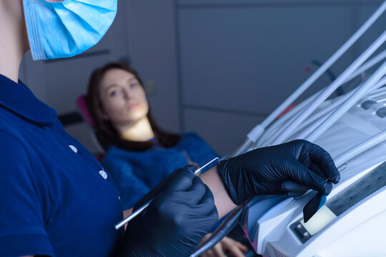 Close-up Of A Dentist Doctor Using Backlight On Equipment, Watching An X-ray Image Of A Tooth, The Patient Is Out Of Focus In The Background. In The Dental Office, Against The Background Of Equipment