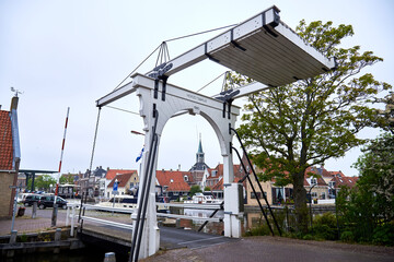 Eine weiße Klappbrücke an einem Kanal in Makkum am Ijsselmeer in den Niederlanden