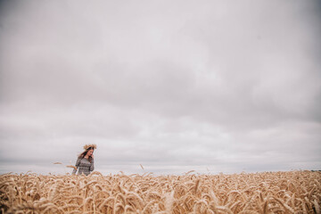 Fototapeta na wymiar Beautiful, slender girl in a field of wheat against the rain sky
