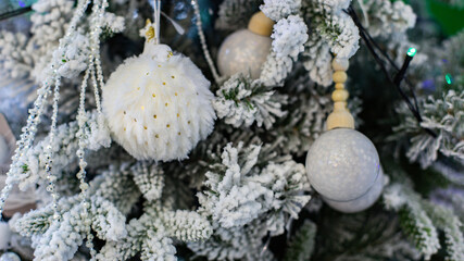 Fluffy white fur ball on a Christmas tree with artificial snow. New Year card background backdrop