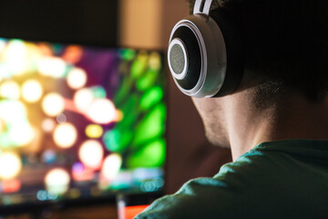 Image of focused man in headphones playing video game on computer