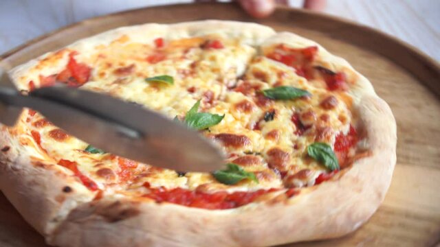 cutting classic pizza margherita with mozzarella and basil, cooking pizza neapolitan at home, fresh hot pizza slice