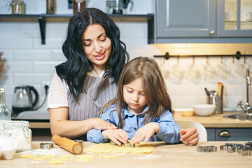 Happy family mother and daughter preparing homemade cookies in the kitchen