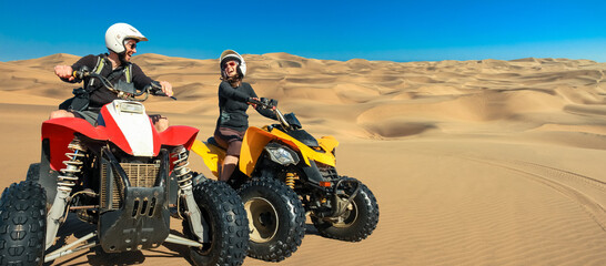 Quad ATV driving people. Happy smiling couple bikers in sand desert. Quad driving and skidmarks in...