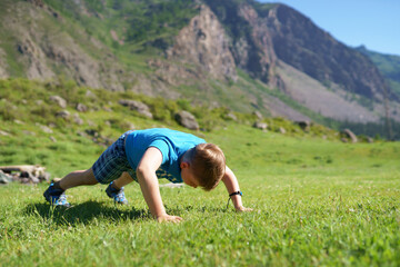 Obraz premium the boy is pushing up on his hands from the ground in the mountain