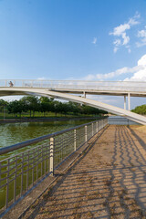Vertical view of a bridge and fence, over canal with blue summer sky, in Juan Carlos I park in Madrid, Spain