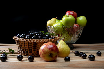 fruits in an arrangement on a light rustic wooden surface with a black background. selective focus.