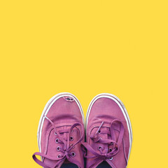 Pair of old weathered sneakers isolated on yellow background. Top view worn out shoes with copy space