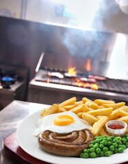 Sausage with eggs, potato chips and green peas served in a plate