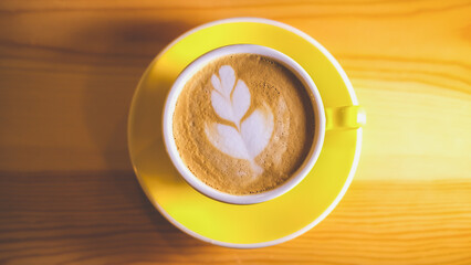 A cup of coffee decorated with a flower drawing with milk in a coffee shop