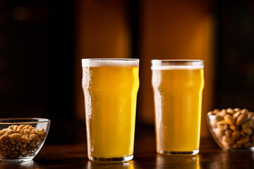 Beer set in pub. Two glasses of ale, nuts and pistachios on table in interior