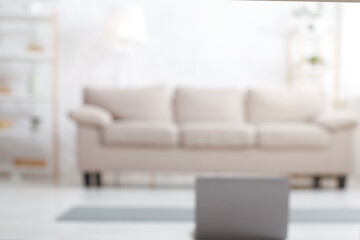 Stay home and work as coach for blog. Laptop, sport mat on floor and sofa in living room