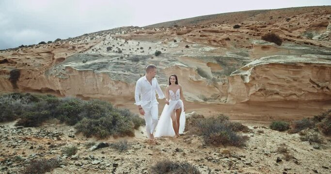 Guy and lady walking through the rocks in amazing landscape view they wearing beautiful dress code enjoying the moment together. 4k