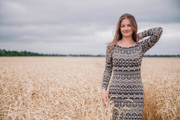 Beautiful, slender girl in a field of wheat against the rain sky