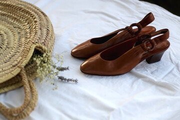 Fototapeta na wymiar Wicker bag with flowers and brown vintage shoes. Selective focus.