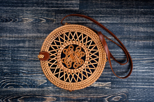 Modern stylish round straw bag on the wooden background, close up