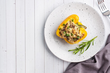 Stuffed sweet peppers with rice mushrooms and cheese with herbs. Baked halves of yellow peppers with filling. White wooden background. Copy space,