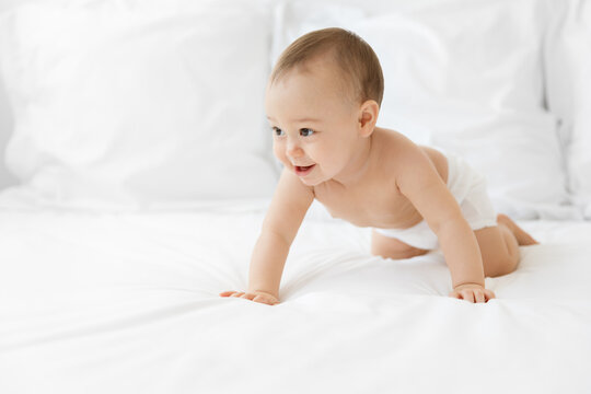 Cute smiling baby crawling on white bed