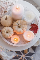 Obraz na płótnie Canvas Autumn home decor with white pumpkins and burning candles.