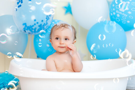baby boy bathes in a bathtub with balloons and soap bubbles, happy childhood, children's birthday