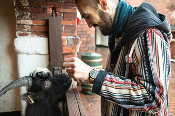 Young men feeding,cuddling and hugging a goat in a farm