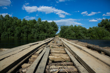 Fototapeta premium Damage bridge. Old wooden bridge through the river with green trees on the banks