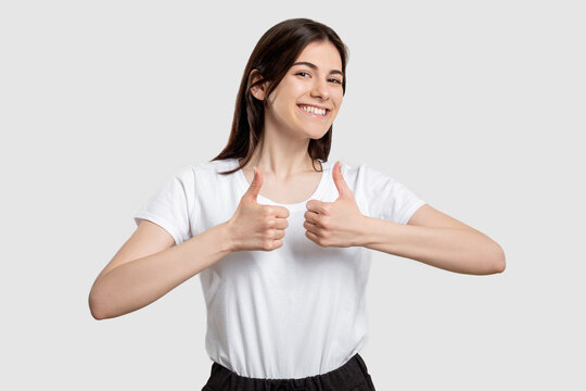 Like gesture. Super great. Cheerful woman showing thumbs up isolated on light background.