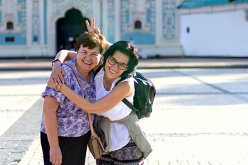 The friendship of two adult women lasts for a very long time Happy friends hug and hold each other, smile. Women travel together. Concept of female friendship.