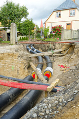 underground heating system pipes replacement on the city street among the houses.