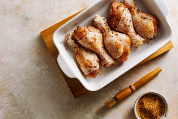 Raw marinated chicken drumstick prepared for baking. Top view.