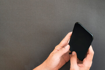 Mobile phone with finger pressing button on dark grey paper texture background