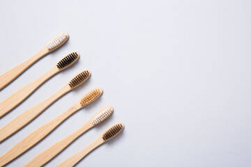 Top view of Bamboo toothbrushes aligned on grey background.