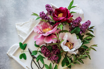 Pink and purple peonies and lilacs on a white tray