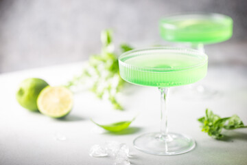 Summer green cocktail with lime, basil and ice in a crystal glass