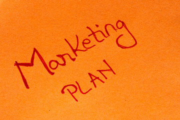 Marketing plan handwriting text close up isolated on yellow paper with copy space.