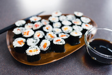 plant-based food, vegan sushi with seaweed and sticky rice with capsicum on serving tray next to bowl with soy sauce
