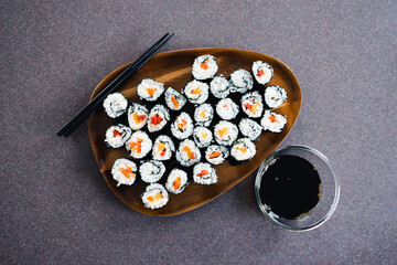 plant-based food, vegan sushi with seaweed and sticky rice with capsicum on serving tray next to bowl with soy sauce
