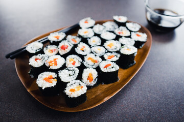 plant-based food, vegan sushi with seaweed and sticky rice with capsicum on serving tray next to bowl with soy sauce