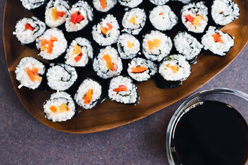 plant-based food, vegan sushi with seaweed and sticky rice with capsicum on serving tray next to bowl with soy sauce