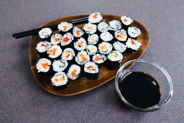 plant-based food, vegan sushi with seaweed and sticky rice with capsicum on serving tray next to bowl with soy sauce