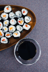 plant-based food, vegan sushi with seaweed and sticky rice with capsicum on serving tray next to bowl with soy sauce