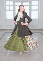 Beautiful woman in long green medieval dress and frock-coat dancing